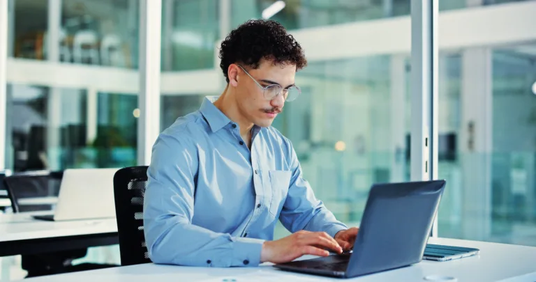 Man working on a laptop in a modern office with a cloud phone system